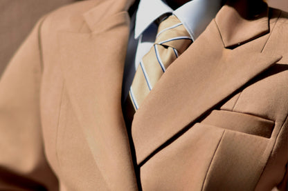 Close-up of a person wearing a beige suit with a patterned tie.