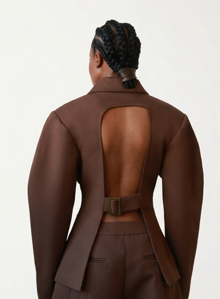 Person wearing a brown suit with open back on a white background